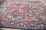 Rich, aged floral patterns and blue border detailing on an antique Persian Kermanshah rug.
