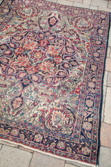 Decorative late 19th century Kermanshah rug featuring ruby red florals and a dark blue border.