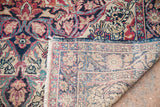 Antique Persian Kermanshah rug corner, intricate red, navy, beige floral pattern, and hand-knotted back.