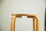 Curved light plywood legs and round wood top detail of the vintage high stool.