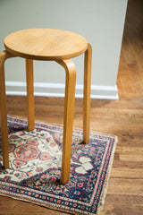 Lower curved light wood legs of the mid-century Alvar Aalto stool.