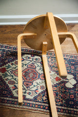 Underside of vintage Aalto style stool's curved light wood legs on a medallion antique rug.