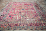 Distressed 9x12 Persian Kerman rug features a faded rose pink field with intricate floral patterns.