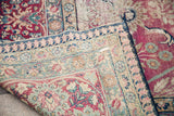 Faded red and pastel floral borders of a distressed vintage Kerman rug.
