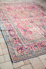 Faded rose and ruby floral borders on a distressed vintage Persian Kerman rug.