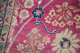 Distressed magenta pile with soft cream and blue floral patterns on a vintage Kerman rug.