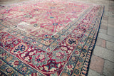 Distressed floral border and faded rose main field of a 1920s Persian Kerman rug.