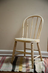 Chippy ivory white finish with light yellow details on an antique child's Windsor chair.