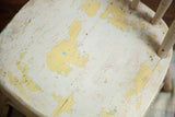 Chippy ivory white and light yellow paint texture on antique child's Windsor chair seat.