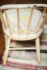 Chipped ivory and yellow paint finish on the antique child's Windsor chair.