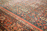 Corner detail of antique Fereghan carpet showcasing green field with pomegranate design and vivid floral border.
