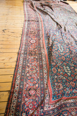 Patinaed madder red border and deep green field of an antique Persian pomegranate rug.