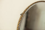 Decorative brass frame and scalloped beveled glass detail of the antique round mirror.