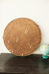 Reverse side of the antique round mirror, with aged brown backing and wire hanger.