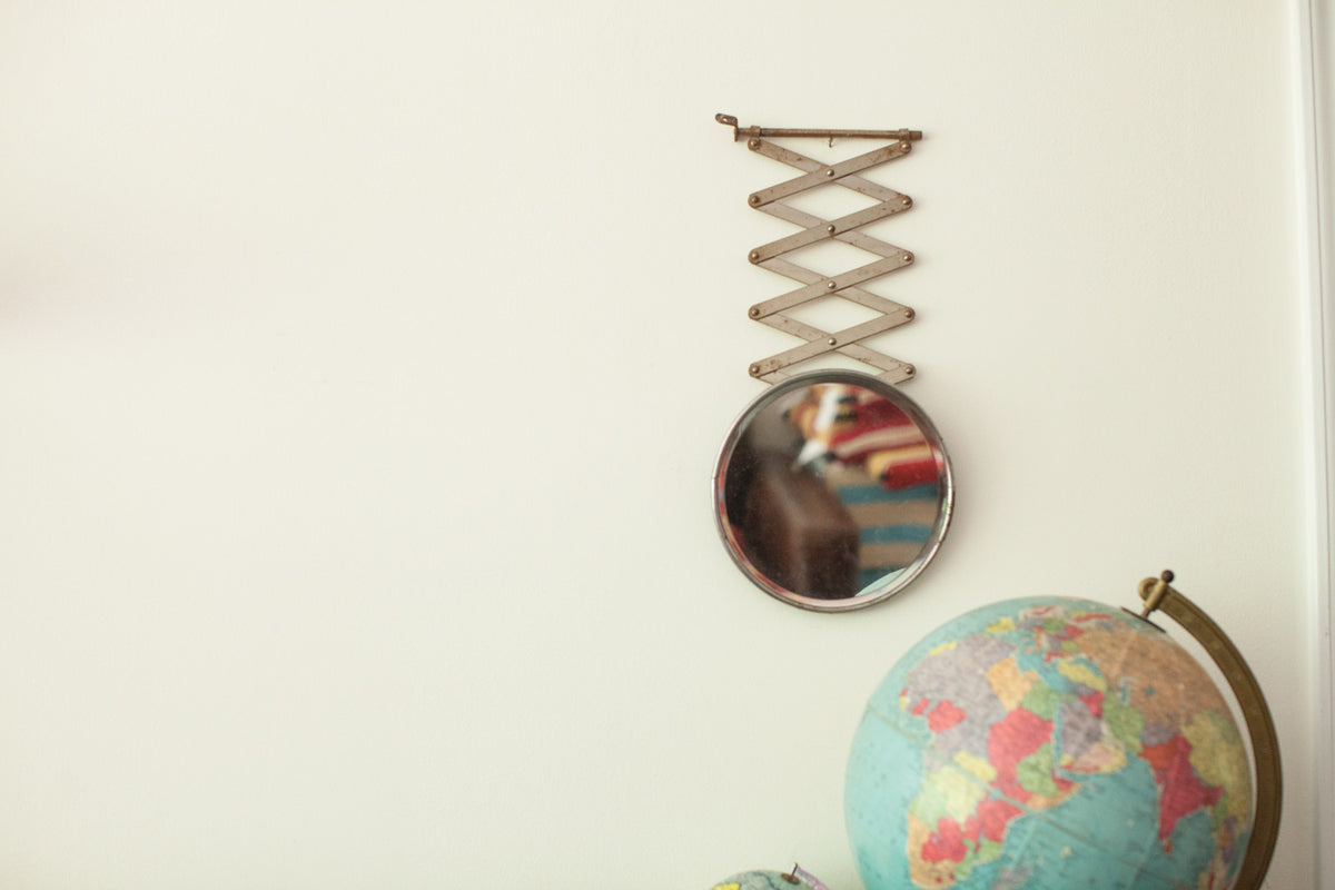 Vintage beveled glass shaving mirror with an accordion arm and aged metal patina.