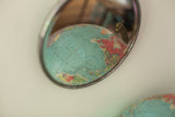 Vintage beveled glass shaving mirror reflecting a colorful vintage globe, showcasing the beveled edge.