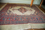Distressed edge of the antique Persian Serab rug, with tattered fringe and red, teal border.