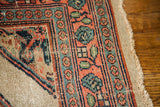 Distressed geometric border in coral, teal, and navy with exposed foundation on an antique Persian rug.