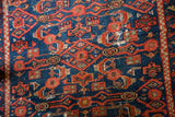 Finely woven Malayer rug detail: indigo blue ground, intricate red-orange herati design.