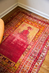 Worn red and golden yellow pile with intricate patterned borders of an antique Turkish prayer rug.