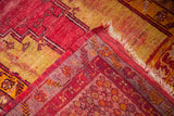 Distressed red and golden yellow Turkish rug corner, with worn pile and tattered fringe.