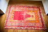 Distressed vintage Turkish prayer rug, showing its worn red pile and golden mihrab pattern.