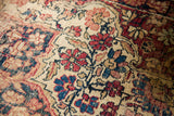 Decorative distressed texture of the Kerman rug, featuring ruby red and deep blue floral designs.