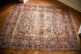 Decorative distressed blue and red floral patterns on an antique Kerman rug corner.