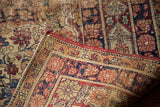 Antique Kerman rug fold showcasing distressed red, blue, and sand patterned texture.