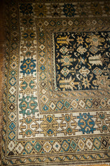 Antique Caucasian rug corner: intricate geometric borders and unique teal, gold serpent motifs.
