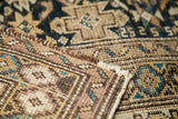 Close-up of the antique Caucasian rug's edge, showing tight weave and muted earth tones.