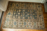 Corner of antique Caucasian rug, abrashed teal field with geometric motifs, earth-tone borders.
