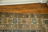 Frayed end of an antique Caucasian rug displaying a minor tear and geometric borders.