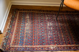Tattered Caucasian rug featuring distressed red ground and repeating blue boteh motifs.