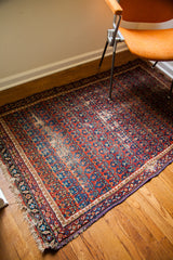 Distressed repeating boteh pattern with red, blue, and rainbow shades on a Caucasian rug.