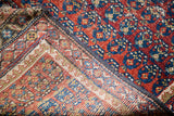Tightly woven foundation and distressed red, blue geometric pile of the Caucasian rug.