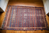 Worn corner detail of the tattered Caucasian rug, showing its fringe and edge.