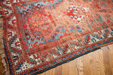 Colorful geometric patterns and storied worn aesthetic on an antique Caucasian rug.