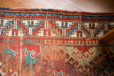 Vibrant stepped geometric border and worn pile on a colorful Caucasian rug.