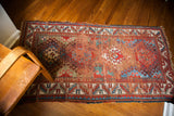 Worn colorful geometric patterns and aged fringe on a vintage Caucasian rug.