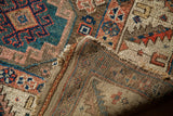Antique Caucasian rug corner showing tribal motifs and striped foundation weave.