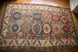 Distinct tribal medallions in varied earth tones and upbeat colors on antique Caucasian rug.