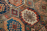 Whimsical geometric patterns and hand-knotted texture on an antique Caucasian tribal rug.