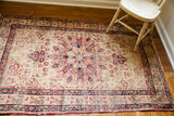 Worn antique Persian Kerman rug corner, blanched ivory with cochineal red scrolling spandrel.