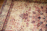 Antique Persian Kerman rug corner, blanched ivory field with cochineal red scrolling spandrels.
