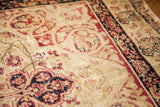 Blanched ivory field with worn cochineal red scrolling patterns on an antique Persian Kerman rug.