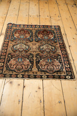 Bottom edge of antique Farahan Sarouk rug showing dark border and earth tone cloudband motifs.