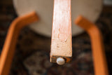 Alvar Aalto style stool leg showing chippy orange paint and white foot cap.
