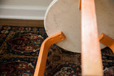 Alvar Aalto style stool underside with chippy orange legs and aged ivory seat.
