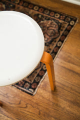 Vintage Alvar Aalto style stool with chippy ivory curved top and orange leg.